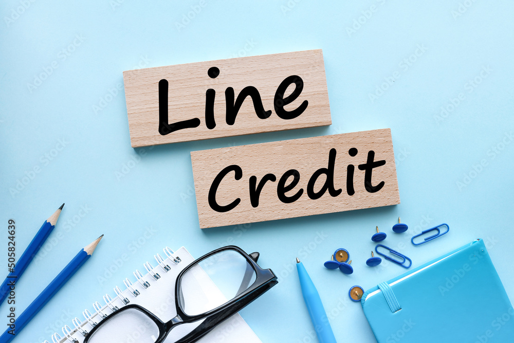 Poster line of credit.open notepad with wooden blocks with text. on a blue background