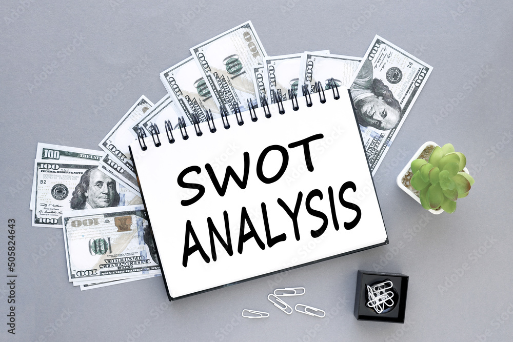 Poster swot analysis. open notepad on dollar bills on a gray background. text on notepad.