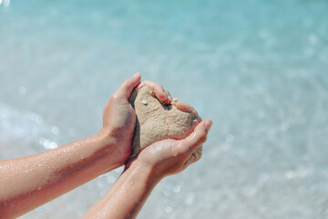 woman holding sand making heart shape sea beach on background