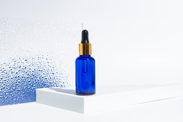 blue glass cosmetic bottle with a dropper on a white background with blue gradient. Natural...