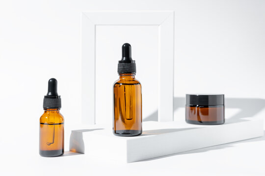 anti-aging collagen facial serum in dark glass bottle and face cream on white background with copy space. Natural Organic Cosmetic Beauty Concept. Mockup for branding