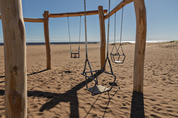 wooden natural children's ecological swing on beach by sea on sunny day