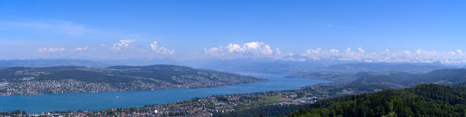 Fototapeta na wymiar Aerial view from local mountain Uetliberg over City of Zürich with Lake Zürich and Swiss Alps in the background on a sunny spring day. Photo taken Mai 18th, 2022, Zurich, Switzerland.