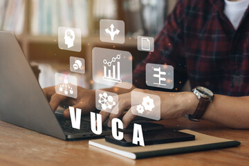Businessmen using a computer to VUCA text surrounded by volatility, uncertainty, complexity,...