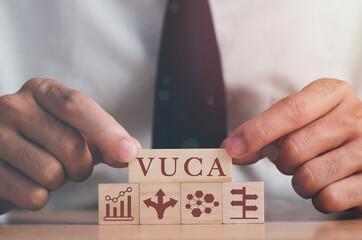VUCA and strategic management. Hand puts wooden cubes with VUCA icon and text volatility,...