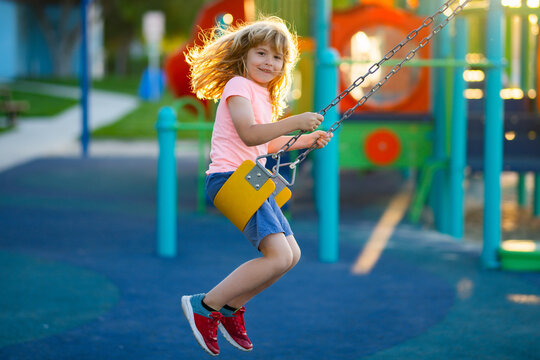 Children Playground In Urban Park. Active Little Child On Playground. Kids Play On School Or Kindergarten Yard. Active Kid On Colorful Swing. Little Boy Swinging.