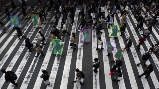 Automated AI facial recognition system image video. Aerial view, crowd of people walking at zebra crossing in Japan. Slow motion shot. Face detection camera, intelligent and technology concept footage
