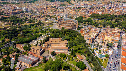 Fototapety  Aerial view of Colosseum and the Arch of Titus, in Italy, on a sunny day. These monuments of ancient Rome are a symbol of the city and visited by many tourists every day.