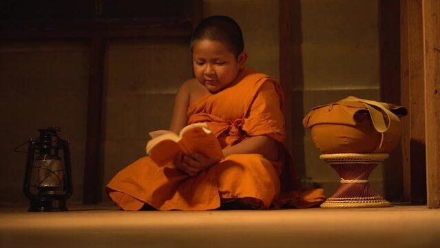 Southeast asian thailand little monk reading book inside monastery, Buddhist teaching. Young novice monk learning inside monastery.
