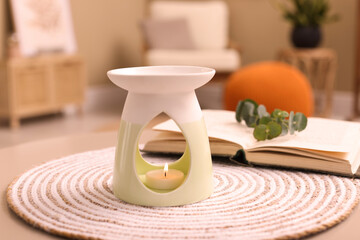 Stylish aroma lamp with small candle on table indoors