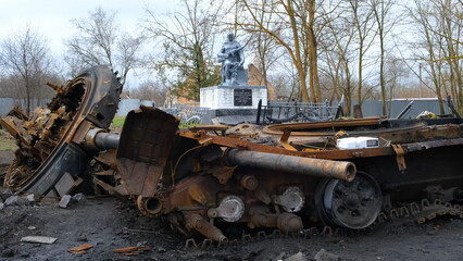a wrecked military vehicle against the backdrop of a monument to a soldier in Ukraine. Irpin-Kyiv- April 2022