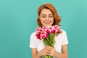happy woman smelling tulip flower bouquet on blue background