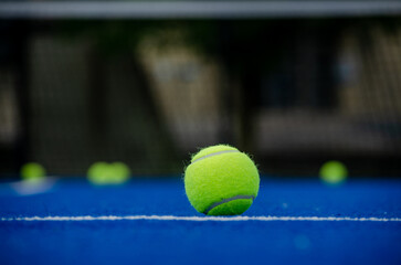 Selective focus, ball in the foreground on a blue paddle tennis court with the background out of...