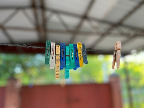 Closeup Of A Few Color Plastic Clothespins. Plastic Clothes Pegs Hanging On A Clothesline. A Clothespin Is A Fastener Used To Hang Up Clothes For Drying. Plastic Clothespins On A Clothesline