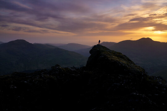 Sunset over the Arrochar Alps, Highlands Scotland with a lone walker taking in the view.
