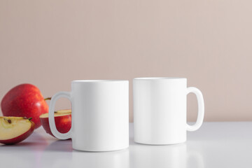 Two mugs coffee mockup and red apples a white table. Empty cup mock up for design. Front view