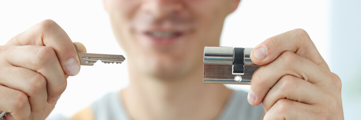 A man locksmith shows a key and a lock, close-up - obrazy, fototapety, plakaty