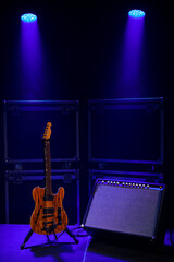Electric guitar with amplifier on stage in the soffits of the concert light