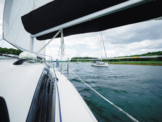 view from sailboat deck on a lake shore and sailing yacht
