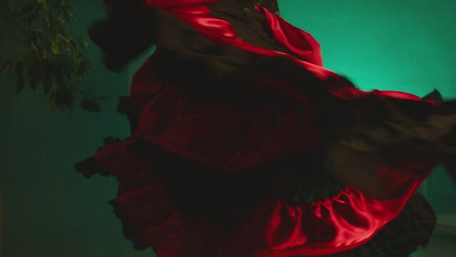 Woman dancing spanish hot dance . Professional dancer in latin dress performs dance movement by skirt . Closeup studio shot of female artist dancing inside dark place . Concept footage of dance art