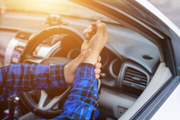 Concept : wrist pain from long driving. Middle-aged man holds his wrist and sits in car. Feeling painful.