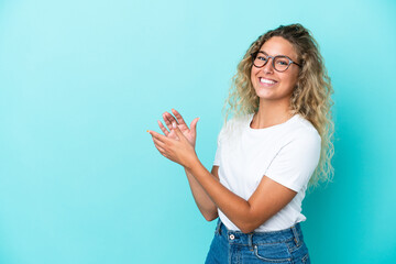 Girl with curly hair isolated on blue background applauding