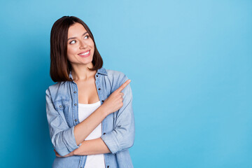 Photo of pretty shiny woman wear jeans shirt looking pointing empty space isolated blue color background