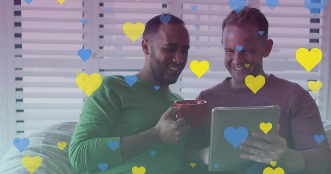 Animation of hearts over diverse gay couple smiling and using tablet