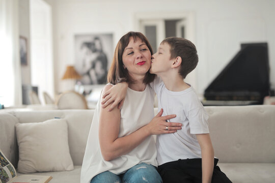 son kisses his mother on the sofa in the house