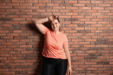 Happy overweight woman near red brick wall