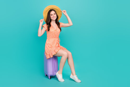 Photo of funny dreamy lady dressed orange clothes straw hat sitting luggage isolated teal color background