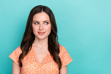 Photo of dreamy adorable woman wear orange outfit looking empty space smiling isolated turquoise color background