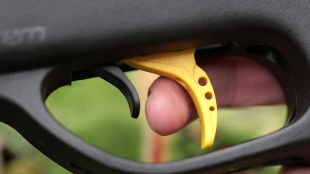 Firing a gun, very close view of a finger pulling the trigger after removing the safety. Macro shot.