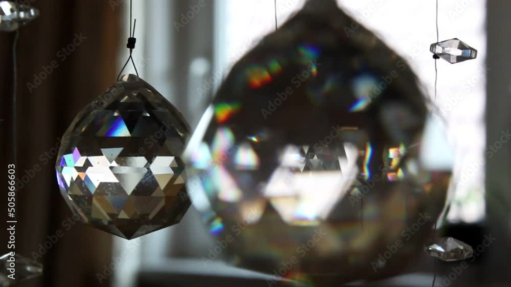 Poster sparkling crystal balls on an expensive chandelier in front of bright windows that let in lots of da