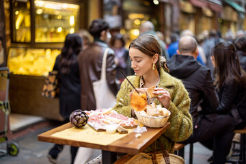 Woman eating italian meat appetizer, various sliced meat and cheese with bread and Aperol Spritz at bar or restaurant outdoors. Concept of Italian lifestyle and gastronomy © rh2010