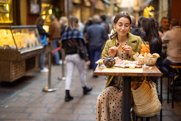 Woman eating italian meat appetizer, various sliced meat and cheese with bread and Aperol Spritz at bar or restaurant outdoors. Concept of Italian lifestyle and gastronomy © rh2010