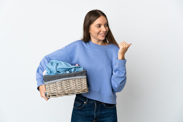 Young Lithuanian woman holding a clothes basket isolated on white background pointing to the side to present a product