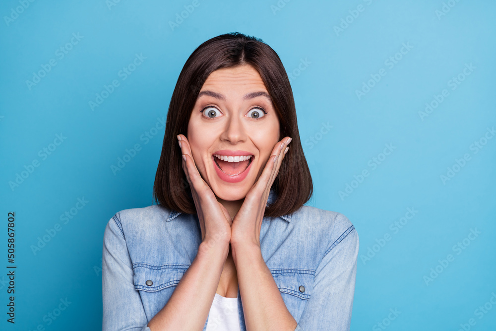 Wall mural Photo of excited cute woman wear jeans shirt arms cheeks open mouth isolated blue color background