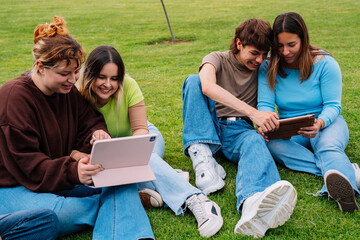 Group of college students using tablets on campus grass