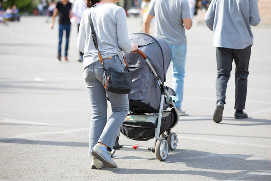 Mother walking in city baby in stroller.