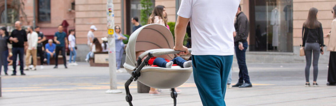 Father walking in city baby in stroller.