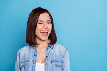 Photo of excited flirty lady dressed denim shirt winking empty space isolated blue color background
