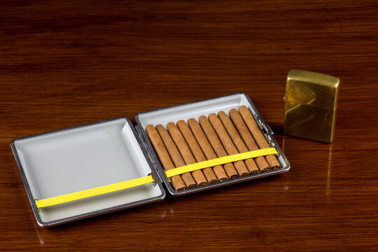 Small Cigars in Cigar Case with Old Lighter on Old Varnished Table Top
