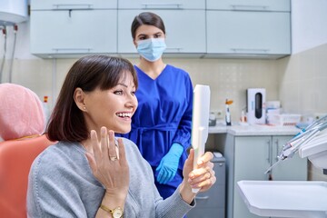 Dentist's office, woman patient looking at her teeth in the mirror