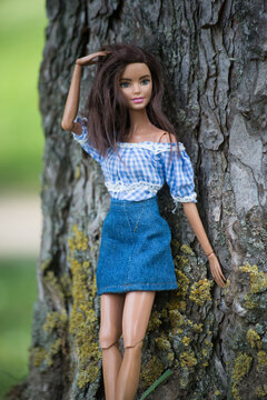Mulhouse - France - 19 May 2022 - portrait of brunette barbie doll wearing a blue jeans skirt standing near a tree trunk in a public garden