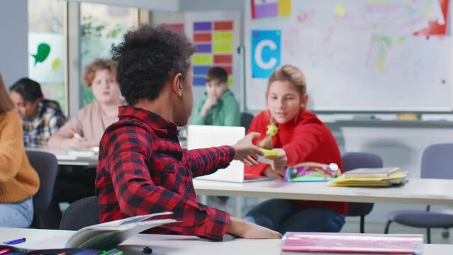 Teen girl pass note to classmate during exam in classroom