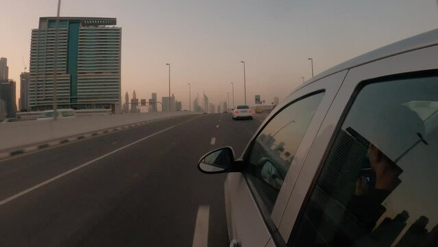 Driving a sedan car on Dubai highway  at sunset Side car view driving in Dubai UAE at sunset on highway with Dubai skyline view