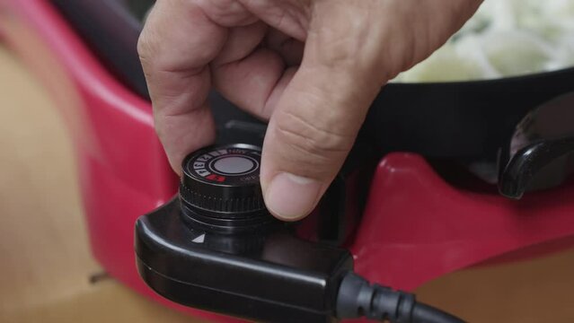 Hand of man is turning on or off the switch and increasing or decreasing the temperature of the BBQ Korean-style grill electric pan.