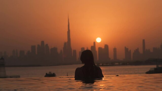 Dubai lifestyle video of travel woman in swimwear enjoying the Dubai skyline view at sunset in an infinity pool. Lifestyle and vacation concept in Dubai UAE
