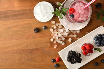 Background with cold drink of berries with fruit and ice around